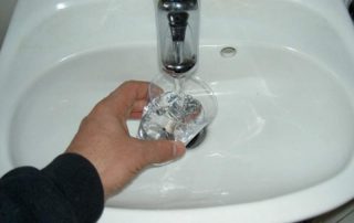 Plastikbecher mit Wasser füllen